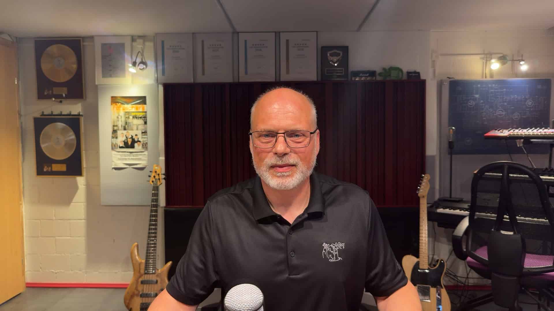 Mastering-Engineer Thom Wettstein vor Gold-Awards und Gitarren in seinem Studio
